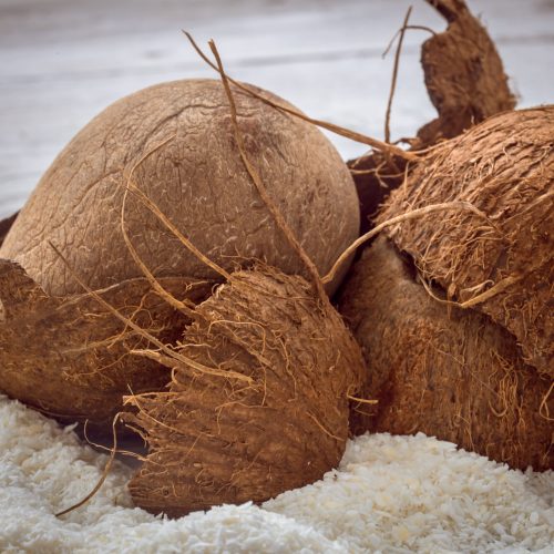 coconut-whole-nuts-scattered-shavings-wooden-table